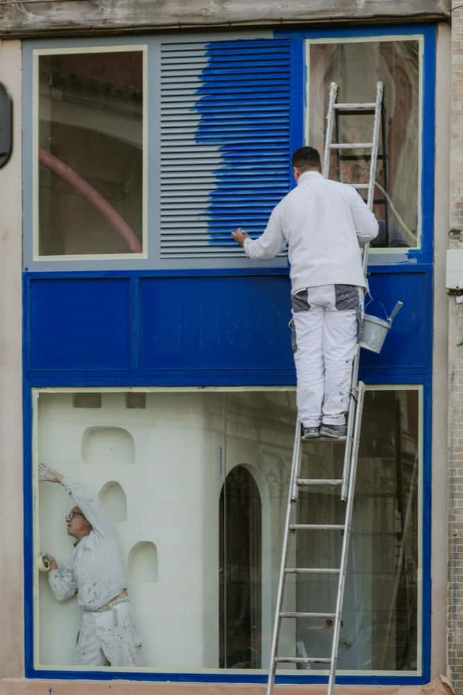 Maler streicht Fensterrahmen an einer Fassade