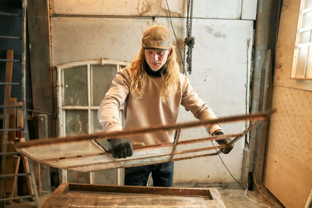 Schreiner mit restauriertem Fensterflügel in der Werkstatt